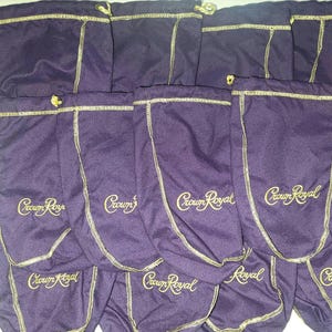 May include: Multiple purple drawstring bags with gold embroidery. The bags feature the text "Crown Royal" in a cursive font.