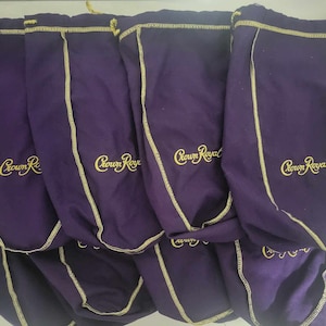 May include: Several purple drawstring bags, each with gold stitching and the "Crown Royal" logo embroidered in gold. The bags are made of a soft fabric and have a drawstring closure at the top.