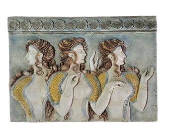 May include: A rectangular, light blue relief sculpture featuring three classical figures with detailed hairstyles and draped garments. The figures have yellow and blue accents, and the top border has a repeating floral pattern.