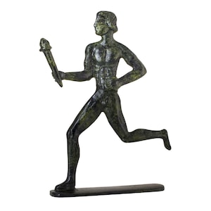 May include: A bronze statue of a running figure holding a torch. The figure is depicted in a dynamic pose, with one leg extended and the other bent. The statue has a dark green patina and is mounted on a rectangular base.