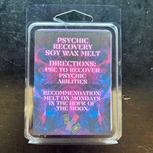 Könnte beinhalten: Eine transparente Kunststoffverpackung mit einem Sojawachs-Schmelzprodukt. Das Etikett trägt den Text "PSYCHIC RECOVERY SOY WAX MELT" in Weiß und Rosa sowie Anweisungen und Empfehlungen zur Verwendung. Der Hintergrund ist eine Mischung aus Blau, Rosa und Lila.