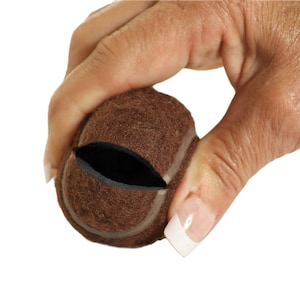 May include: A brown tennis ball with a black seam is split open, revealing the inside of the ball.