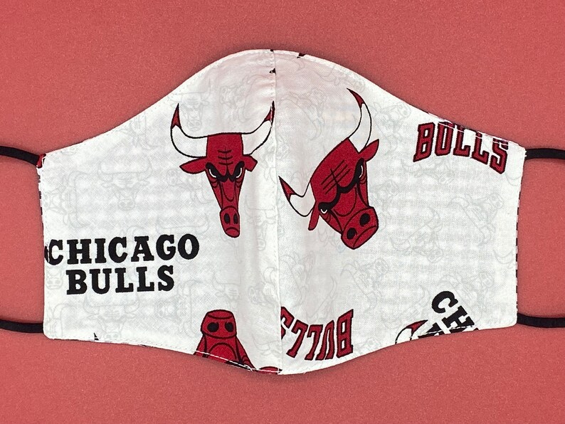 Puede incluir: M&aacute;scara facial blanca con un logotipo de los Chicago Bulls en rojo y negro y las palabras "Chicago Bulls" y "Bulls".