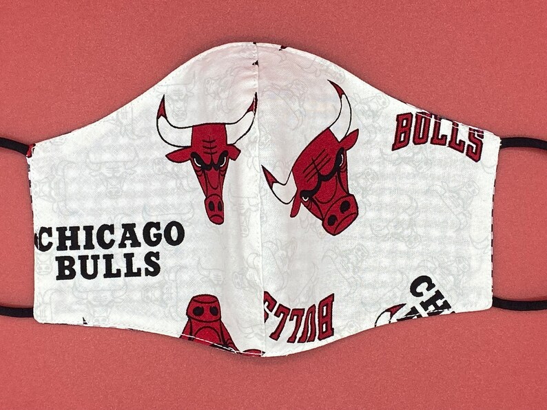 Puede incluir: M&aacute;scara facial blanca con un patr&oacute;n repetido de logotipos rojos de los Chicago Bulls y el texto "Chicago Bulls" y "Bulls".