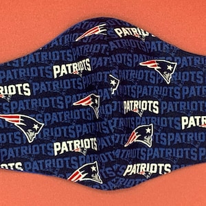 Puede incluir: Una mascarilla facial azul con un patr&oacute;n repetido del logotipo de los New England Patriots y la palabra "Patriots" en blanco.