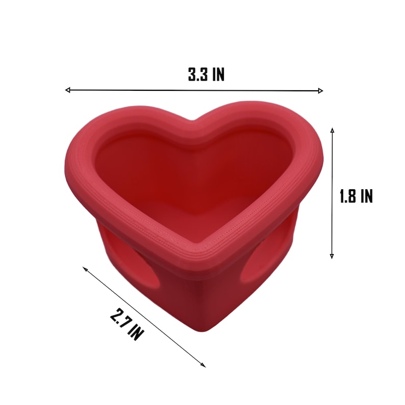 May include: A red heart-shaped container, 3.3 inches wide, 2.7 inches long, and 1.8 inches high. The container has a smooth, rounded rim and two small holes on the sides. The object is on a white background.