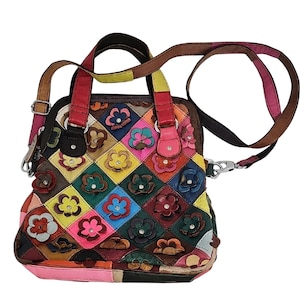 Puede incluir: Bolso de mano patchwork colorido con aplicaciones florales. El bolso presenta una mezcla de colores como rosa, amarillo, verde y azul. Tiene un asa superior y una correa de hombro desmontable.