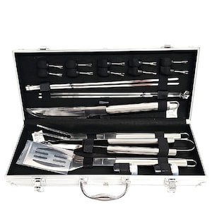 May include: A stainless steel barbecue tool set in a silver aluminum case. The set includes a knife, spatula, tongs, skewers, and other grilling utensils. The case is lined with black fabric and secured with black straps.