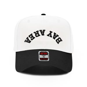 Pode incluir: Um boné de beisebol branco e preto com o texto "BAY AREA" em preto, arqueado na frente. O boné tem uma aba curva e um pequeno botão preto na parte superior. O boné tem uma etiqueta "OTTO".