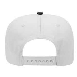May include: A white snapback hat with a black button on top and a white adjustable strap. The hat is made of a durable fabric and features a classic, flat brim design. The back of the hat is visible, showing the adjustable strap.