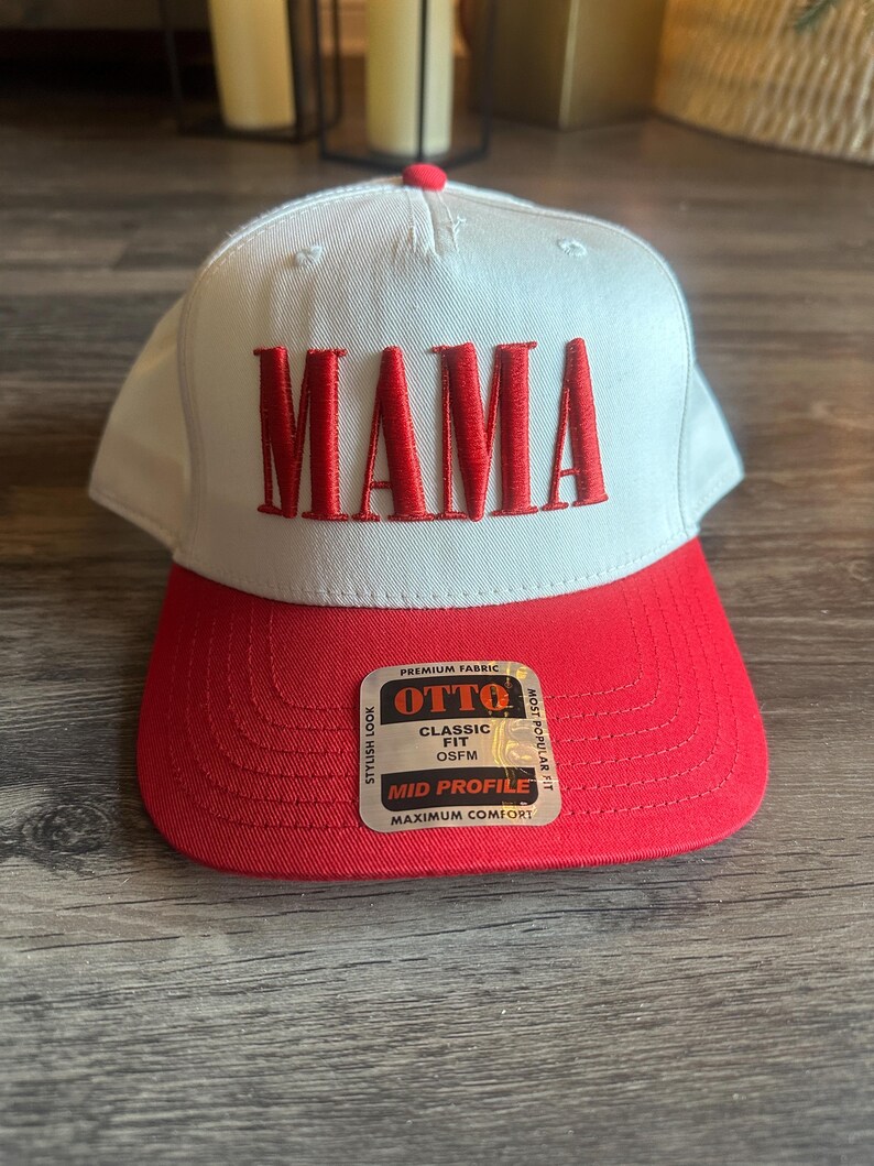 Pode incluir: Bon&eacute; de beisebol branco com aba vermelha e a palavra "MAMA" bordada em vermelho na frente. O bon&eacute; tem uma etiqueta lateral que diz "OTTO" e "Classic Fit OS FM" e "Mid Profile Maximum Comfort".