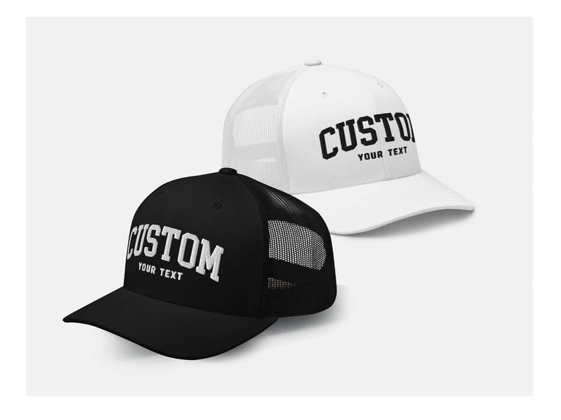 May include: Two trucker hats, one black and one white, with a mesh back. Both hats have the word "CUSTOM" in black lettering with the words "YOUR TEXT" underneath.