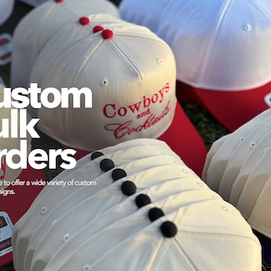 Puede incluir: Una pila de gorras de b&eacute;isbol blancas y beige con botones negros. La gorra de arriba tiene bordado rojo que dice "Cowboys and Cocktails". El texto "Custom Bulk Orders" est&aacute; en letras blancas grandes en la imagen.