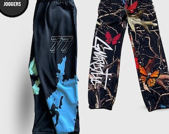 May include: Two pairs of joggers. The left pair is black with a blue and light green abstract map-like pattern and the number 77 in white. The right pair features a camouflage print with red and orange butterflies and white script text.