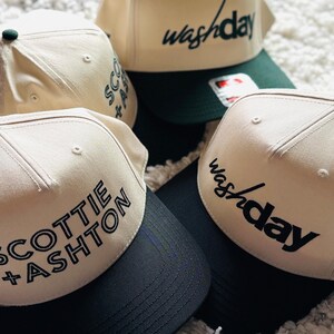 Pode incluir: Quatro bon&eacute;s de beisebol bege com bordados pretos. Dois bon&eacute;s t&ecirc;m o texto "washday" na frente, e dois bon&eacute;s t&ecirc;m o texto "SCOTTIE + ASHTON" na frente. Os bon&eacute;s t&ecirc;m viseiras pretas.