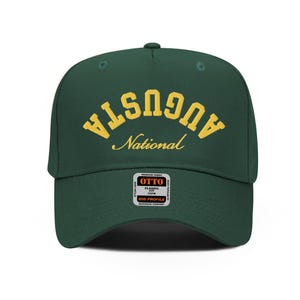 Op de afbeelding: Een groene baseballcap met een geel geborduurd logo met de tekst "Augusta National". De cap heeft een wit label aan de voorkant met de tekst "Otto Classic Fit Mid Profile".