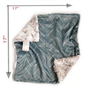 Puede incluir: Una manta suave y mullida para beb&eacute; con un patr&oacute;n de chevron en tonos azules y blancos. La manta mide 43 cm por 43 cm y tiene un respaldo de piel sint&eacute;tica.