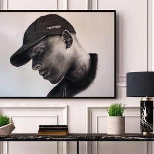 May include: Black and white charcoal drawing of a person wearing a black baseball cap with the word "GREATNESS" written on it. The person has a tattoo on their neck that says "VED".