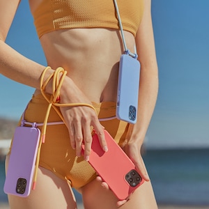 K&ouml;nnte beinhalten: Eine Frau tr&auml;gt ein gelbes Bikini-Oberteil und -Unterteil mit einer blauen Handyh&uuml;lle, die an einem Band um ihren Hals befestigt ist. Sie h&auml;lt eine rosa Handyh&uuml;lle in der Hand.