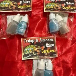 May include: Three small bottles, two clear and one blue, are packaged in clear plastic. Each package has a label with the text "Trabajo de Separacion y Retiro Camaleon Yerberia Zanta Muerte" and a chameleon illustration. The background is red.