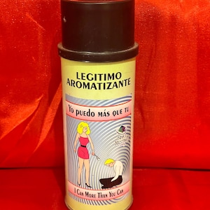 May include: A cylindrical air freshener with a black cap and a yellow label. The label features the text "LEGITIMO AROMATIZANTE" and a cartoon illustration of a woman and a kneeling person. The text "I CAN MORE THAN YOU CAN" is also visible.