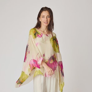 Pode incluir: Um top creme com estampa floral e calças de perna larga. O top apresenta um padrão floral em estilo aquarela em rosa, verde e amarelo. As calças são de cor creme combinando. A roupa é feita de um tecido leve e fluido.