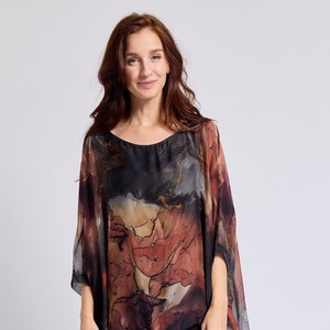 May include: A woman wearing a black and red patterned silk top with a black tiered skirt and black ankle boots.