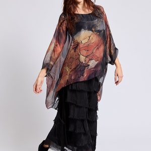 May include: A woman wearing a black and brown patterned silk top with a black tiered skirt and black ankle boots.