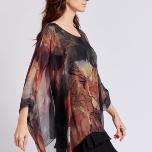 May include: A sheer, flowing top with a black, brown, and red abstract print. The top has a loose, relaxed fit and a slightly asymmetrical hemline.