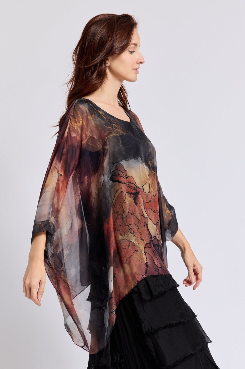 May include: A sheer, flowing top with a black, brown, and red abstract print. The top has a loose, relaxed fit and a slightly asymmetrical hemline.