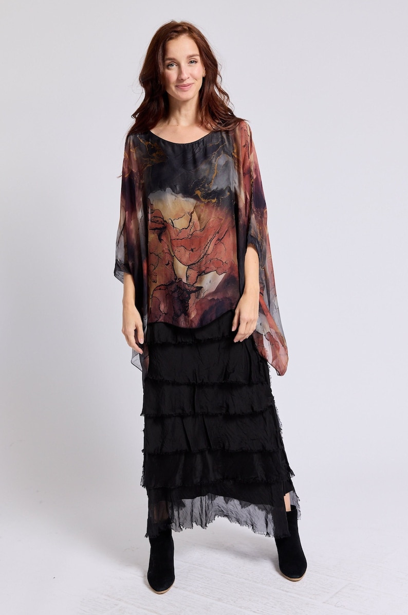 May include: A woman wearing a black and red patterned silk top with a black tiered skirt and black ankle boots.