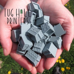 May include: A close-up of a hand holding a pile of small, gray, 3D printed boxes. Each box has the number "2020" printed on it.