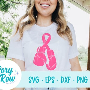 May include: White t-shirt featuring a pink ribbon and boxing gloves design. The design includes the text "SVG • EPS • DXF • PNG" and the Rory Row Design Co. logo. The shirt is a simple, casual style.