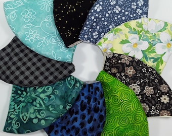 May include: A collection of nine fabric face masks in various patterns, including floral, geometric, and abstract designs. The masks are all in different colors, including green, blue, black, and white.