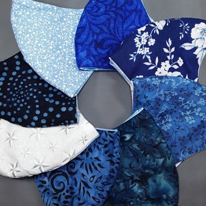 May include: A collection of eight blue and white fabric face masks with various patterns, including floral, paisley, and geometric designs.