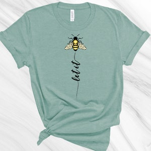 May include: A teal blue t-shirt with a black and yellow bee graphic and the text "let it" printed vertically below the bee.
