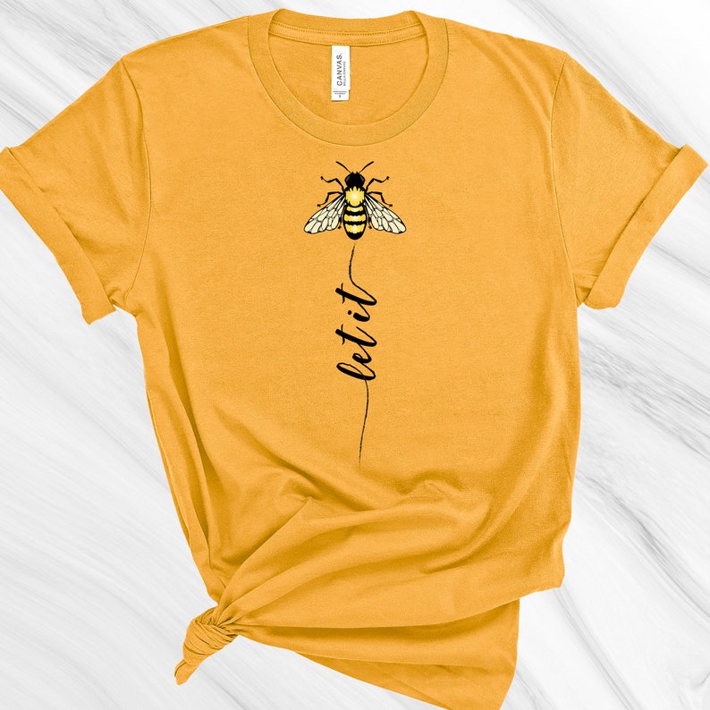 May include: A yellow t-shirt with a black bee graphic and the text "let it" printed on the front.