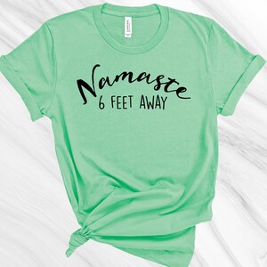 May include: A light green t-shirt with the text "Namaste 6 feet away" printed in black.