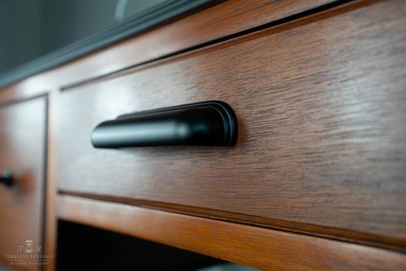 May include: Close-up of a wooden drawer with a black metal pull handle. The drawer is part of a dresser or cabinet.