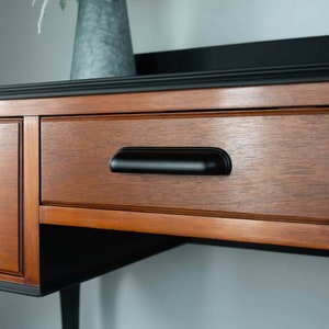 May include: A wooden dresser with two drawers and a black top. The drawers have black metal handles. The dresser is painted black on the top and bottom.