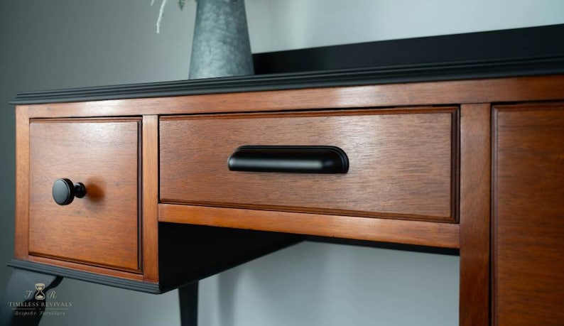 May include: A wooden dresser with two drawers and a black top. The drawers have black metal handles. The dresser is painted black on the top and bottom.
