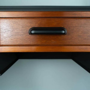 May include: A wooden desk with a black painted top and a drawer with a black pull handle. The desk has a shelf underneath the drawer.