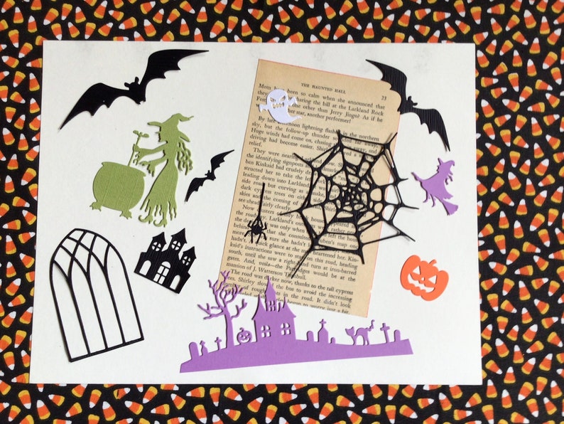 May include: A collection of 12 Halloween-themed paper diecuts, including witches, a cauldron, a spider web, a haunted house, a bats, a pumpkin, ghost, and a graveyard scene.
