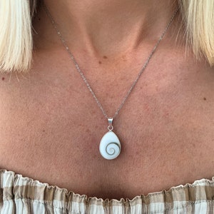 May include: A silver chain necklace with a white shell pendant featuring a spiral pattern.