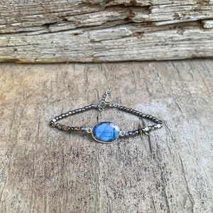 Puede incluir: Una pulsera de plata con una piedra ovalada azul y cuentas de plata.