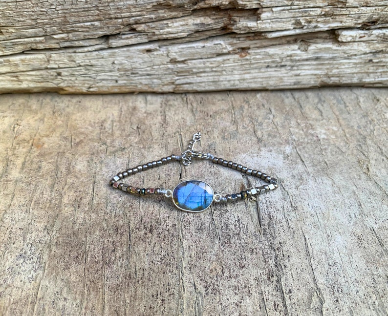 Puede incluir: Una pulsera de plata con una piedra ovalada azul y cuentas de plata.