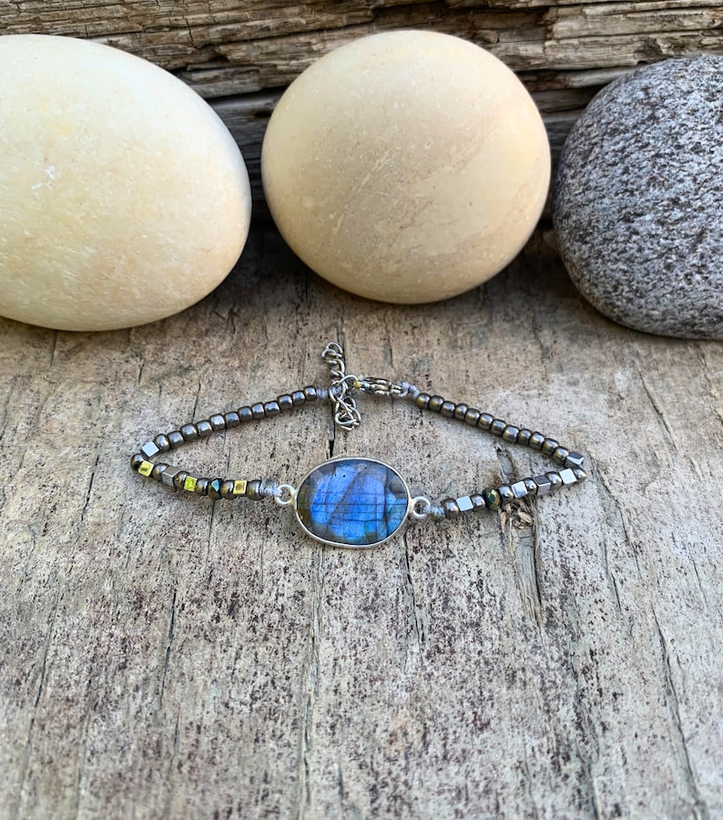 A silver bracelet with a blue labradorite gemstone and hematite beads. Flash color varies.