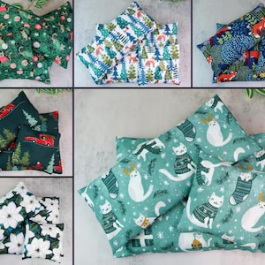 May include: A collection of decorative pillows with various holiday-themed patterns. Designs include cats in sweaters, foxes, Christmas trees, and poinsettias. The pillows are square and made of fabric.