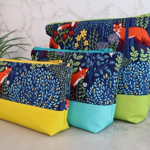 May include: Three zippered pouches with a blue and green floral pattern featuring foxes. The pouches are lined with yellow, turquoise, and green fabric.
