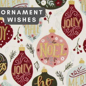 May include: A white fabric featuring a repeating pattern of Christmas ornaments in shades of red, dark green, and light blue. The ornaments are decorated with gold text including Joy, Jolly, Noel, and Merry, alongside small floral and pine sprig motifs.